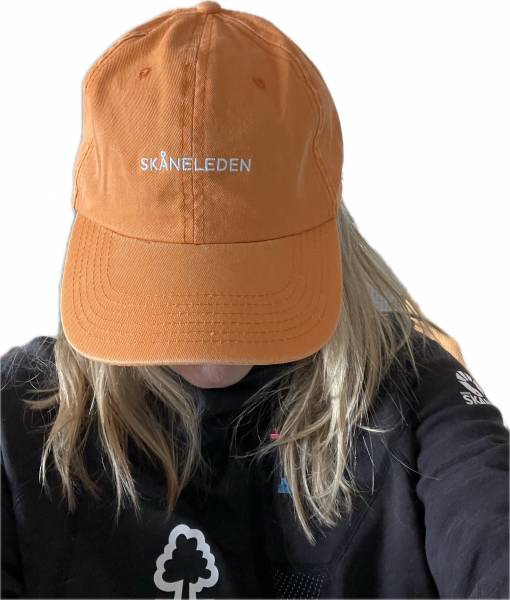 Gul keps med Sk&aring;neleden i text p&aring; framsidan, logotype p&aring; baksidan